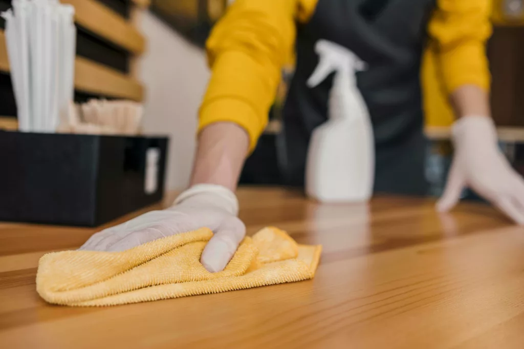 Person cleaning a table with a rag - house cleaning in Ellijay, GA